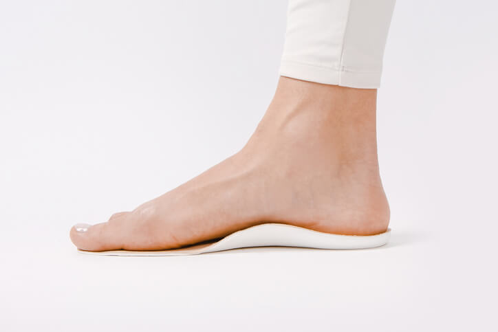 Οι προσαρμοσμένοι λευκοί πάτοι ετοιμάστηκαν η πάσχων τοποθετεί το ένα της πόδι να ελέξει την τέλεια εφαρμογή του.