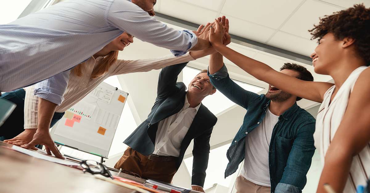 We did it Business people giving each other high-five and smiling while working together in the modern office. Teamwork. Success