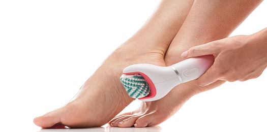Closeup of Female feet and electric foot scrubber or massage device on white background